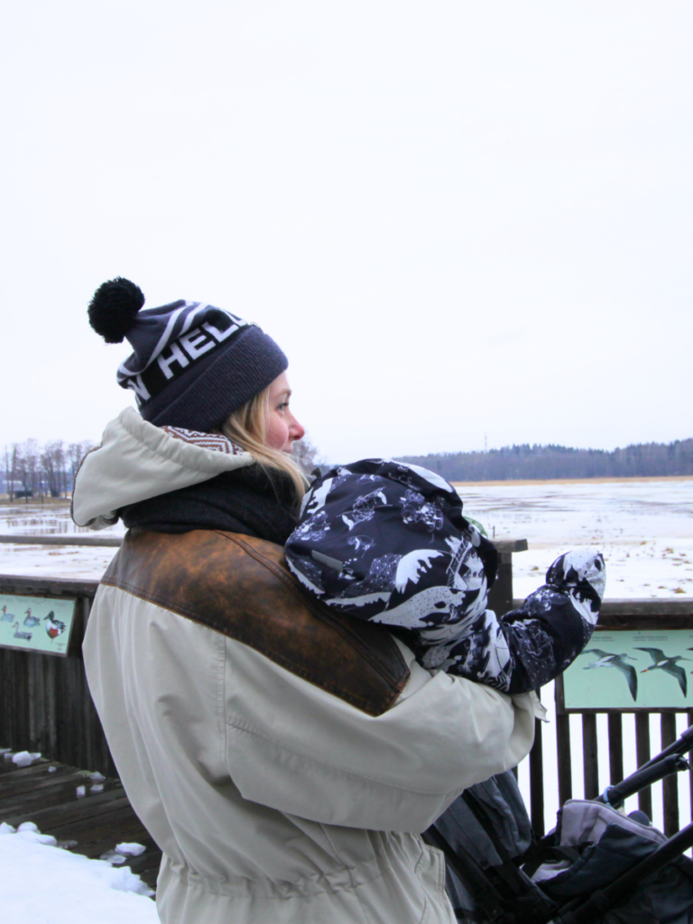 Woman standing on a birdwatching platform holding a baby in Helsinki, Finland.